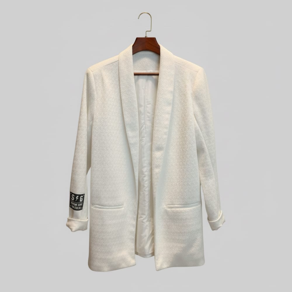 “Blazer Manifiesto blanco crudo, corte recto, largo medio, caída fluida, solapa tipo esmoquin, bolsillos de parche, vinilo MANIFIESTO en espalda, parche STORM UNIT en manga.”